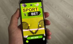 Tennis Raqettes and Balls Below Text Sport Bet on Cell Phone Held in Hand