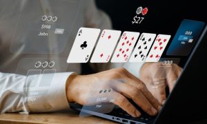 Man Sitting at Desk Uses Laptop to Play Online Poker with 5 Digital Playing Cards Displayed Virtually