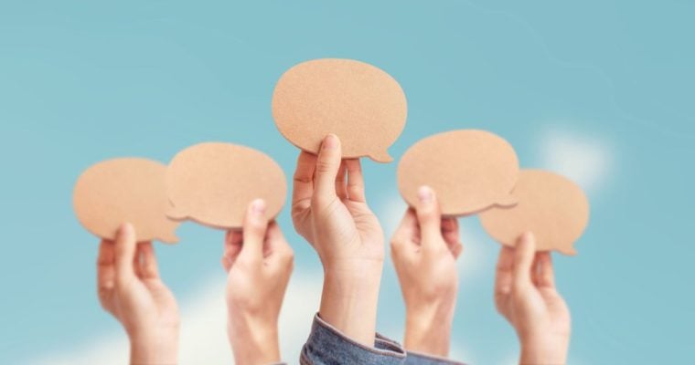 Hands Hold Up Blank Speech Bubbles Against Blue Sky Background