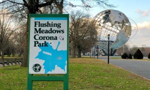 Unisphere Stands In Background with Sign of Flushing Meadows Corona Park in Foreground