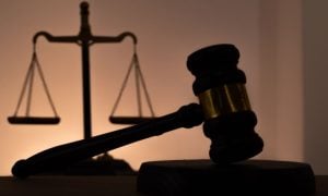 White Wall Highlights the Silhouette of a Scale and Judge's Gavel