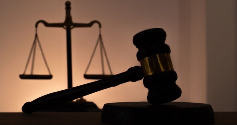 White Wall Highlights the Silhouette of a Scale and Judge's Gavel