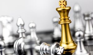 Gold King Chess Piece Stands on the Board Among Silver Pieces