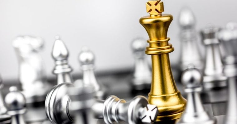 Gold King Chess Piece Stands on the Board Among Silver Pieces