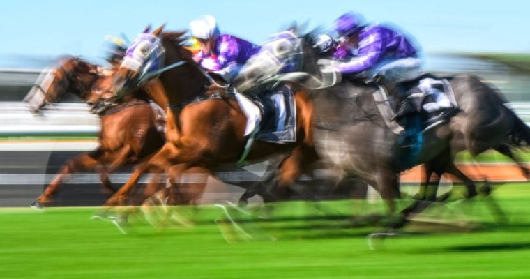 Slow Exposure Shows a Blurred Out Image of Three Horses Racing on A Grass Track