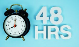 Black Alarm Clock with Phrase 48 HRS on Blue Background