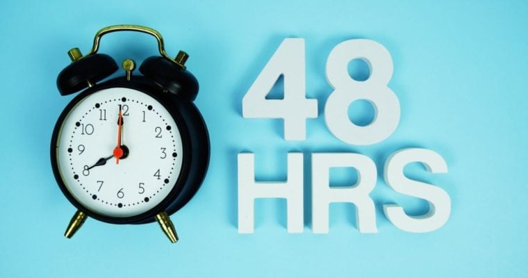 Black Alarm Clock with Phrase 48 HRS on Blue Background