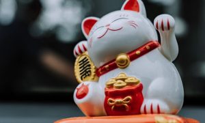 Asian Lucky White Cat Porcelain Figure On Blurred Background