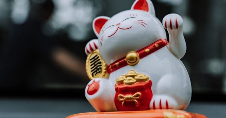 Asian Lucky White Cat Porcelain Figure On Blurred Background