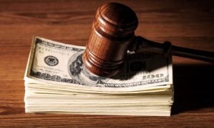 Stack of $100 Banknotes Sits on Wood Table With Wood Judge's Gavel on Top