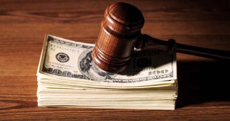 Stack of $100 Banknotes Sits on Wood Table With Wood Judge's Gavel on Top