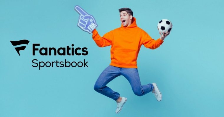 Man Wearing Jeans and Orange Hoodie Holds Soccer Ball While Jumping Next To Fanatics Sportsbook Logo