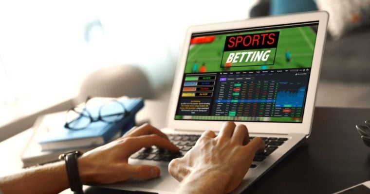 Man Uses Laptop To Access Sports Betting While Sitting At Desk