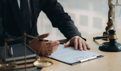 Man in Suit Sits At Desk Reviewing Legal Document