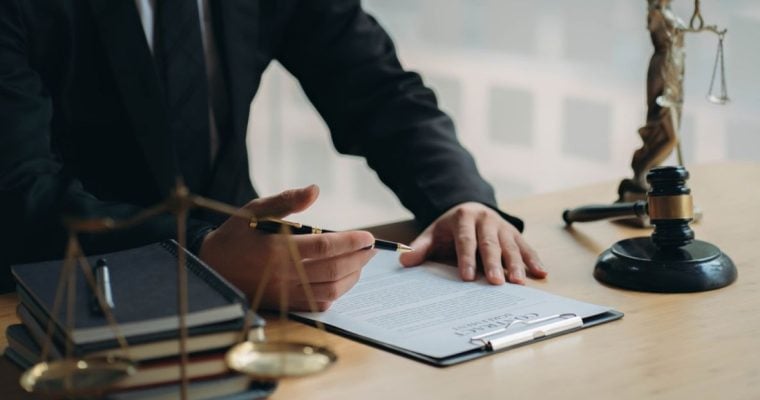 Man in Suit Sits At Desk Reviewing Legal Document
