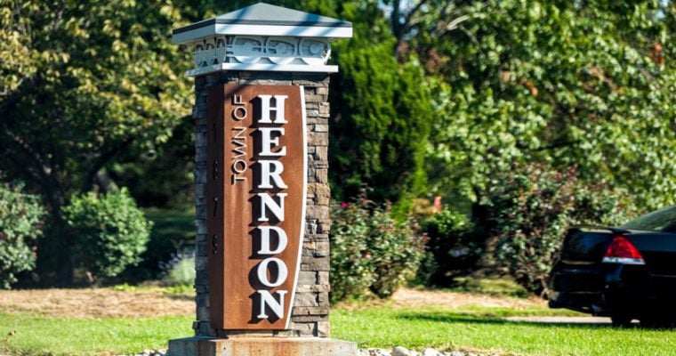 Green Trees Surround Outside Sign That Says Town of Herndon