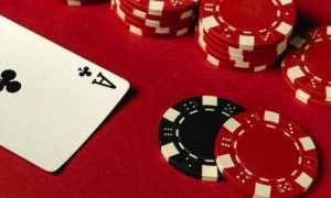 Stacked Red Poker Chips Lay on Red Game Table with Ace of Clubs Playing Card