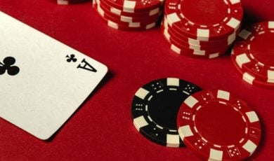 Stacked Red Poker Chips Lay on Red Game Table with Ace of Clubs Playing Card