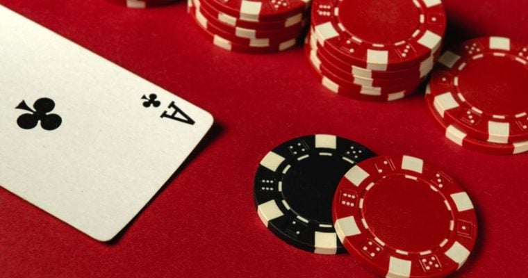 Stacked Red Poker Chips Lay on Red Game Table with Ace of Clubs Playing Card