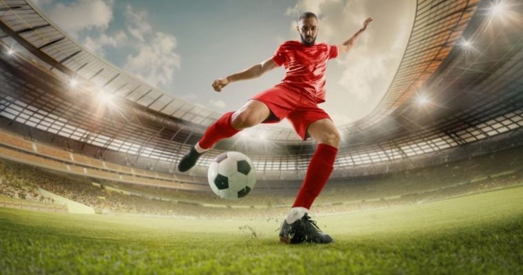 Soccer Player in Red Uniform Kicks Soccer Ball on Green Grass Field