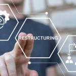 Man Points with Two Fingers to the Word Restructuring in Digital Icon Overlay