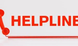 Red Telephone with Wire Corde Sits Below the Word Helpline in Red Letters