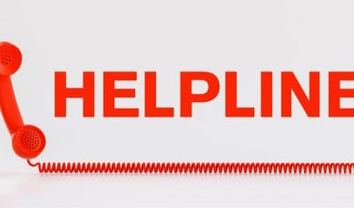 Red Telephone with Wire Corde Sits Below the Word Helpline in Red Letters