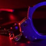 Red and Blue Lights Shine on Metal Handcuffs Sitting on Table