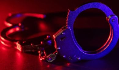 Red and Blue Lights Shine on Metal Handcuffs Sitting on Table