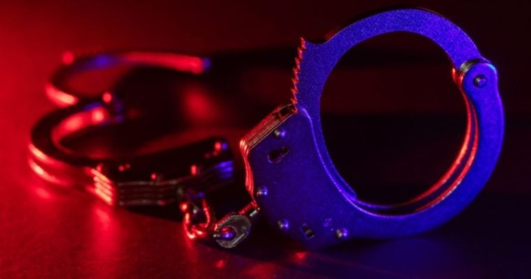 Red and Blue Lights Shine on Metal Handcuffs Sitting on Table