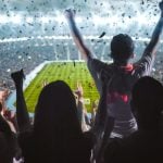 Soccer Fans Fill Brightly Lit Stadium and Cheer While Facing Field