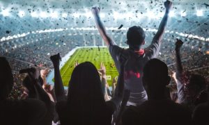 Soccer Fans Fill Brightly Lit Stadium and Cheer While Facing Field