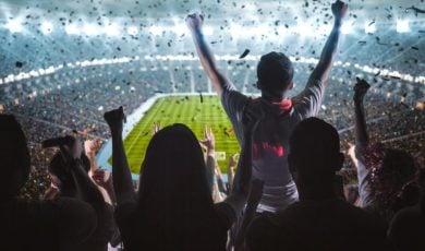Soccer Fans Fill Brightly Lit Stadium and Cheer While Facing Field