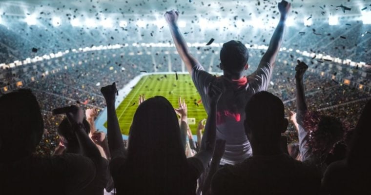 Soccer Fans Fill Brightly Lit Stadium and Cheer While Facing Field