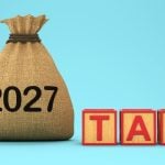 Brown Pouch Says 2027 Sitting Next To Wooden Blocks Spelling the Word TAX in Red