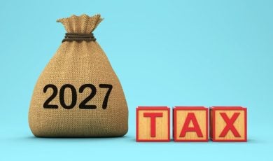 Brown Pouch Says 2027 Sitting Next To Wooden Blocks Spelling the Word TAX in Red