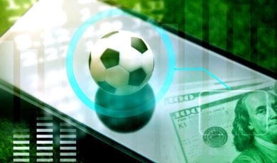 Soccer Ball Sits On Top of Mobile Phone with $100 Bills Cash Sitting at Bottom Right Corner