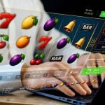 Man Plays Fruit-Themed Online Slot Game with Laptop