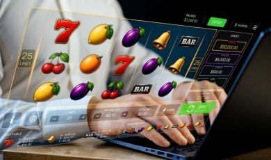 Man Plays Fruit-Themed Online Slot Game with Laptop