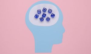 Art Collage of Head Made with Blue Paper and Blue Dice Inside on Pink Background