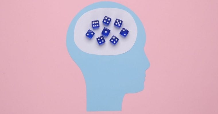 Art Collage of Head Made with Blue Paper and Blue Dice Inside on Pink Background