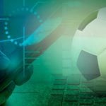 Soccer Ball Sits on Compute Keyboard with Man Holding Cell Phone in Online Sports Betting Concept