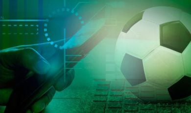 Soccer Ball Sits on Compute Keyboard with Man Holding Cell Phone in Online Sports Betting Concept