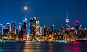 Night Time View of NYC Buildings on the Waterfront with Moon Hanging Above