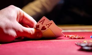 Man Plays Poker Reveals Two Aces on Red Gaming Table With Chips