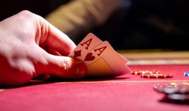 Man Plays Poker Reveals Two Aces on Red Gaming Table With Chips