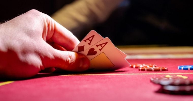 Man Plays Poker Reveals Two Aces on Red Gaming Table With Chips