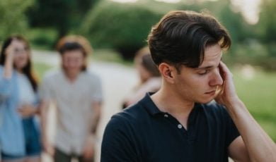 Man with Anxiety and Social Problem Excludes Himself From Friend Group in Background
