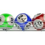 Yellow, Green, Blue, Red and Orange Numbered Lottery Balls Sit on Silver Metal Rack