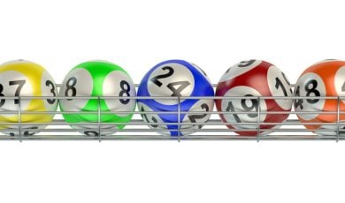 Yellow, Green, Blue, Red and Orange Numbered Lottery Balls Sit on Silver Metal Rack